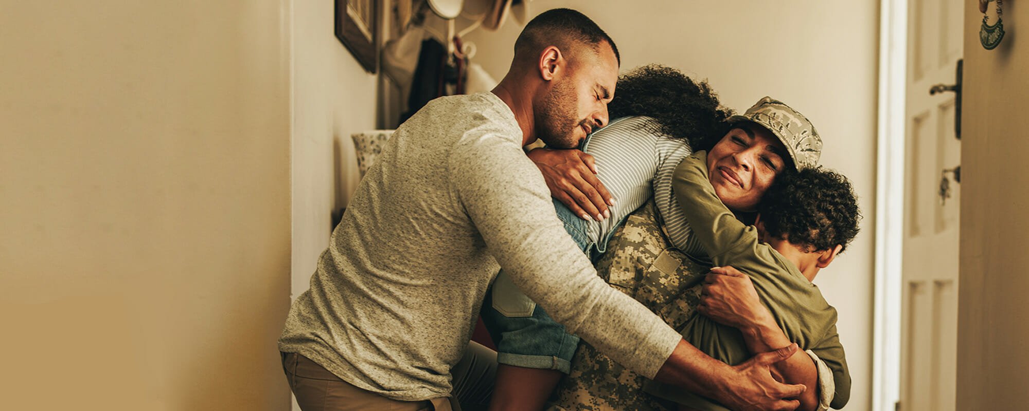 A veteran in uniform hugging their family at home