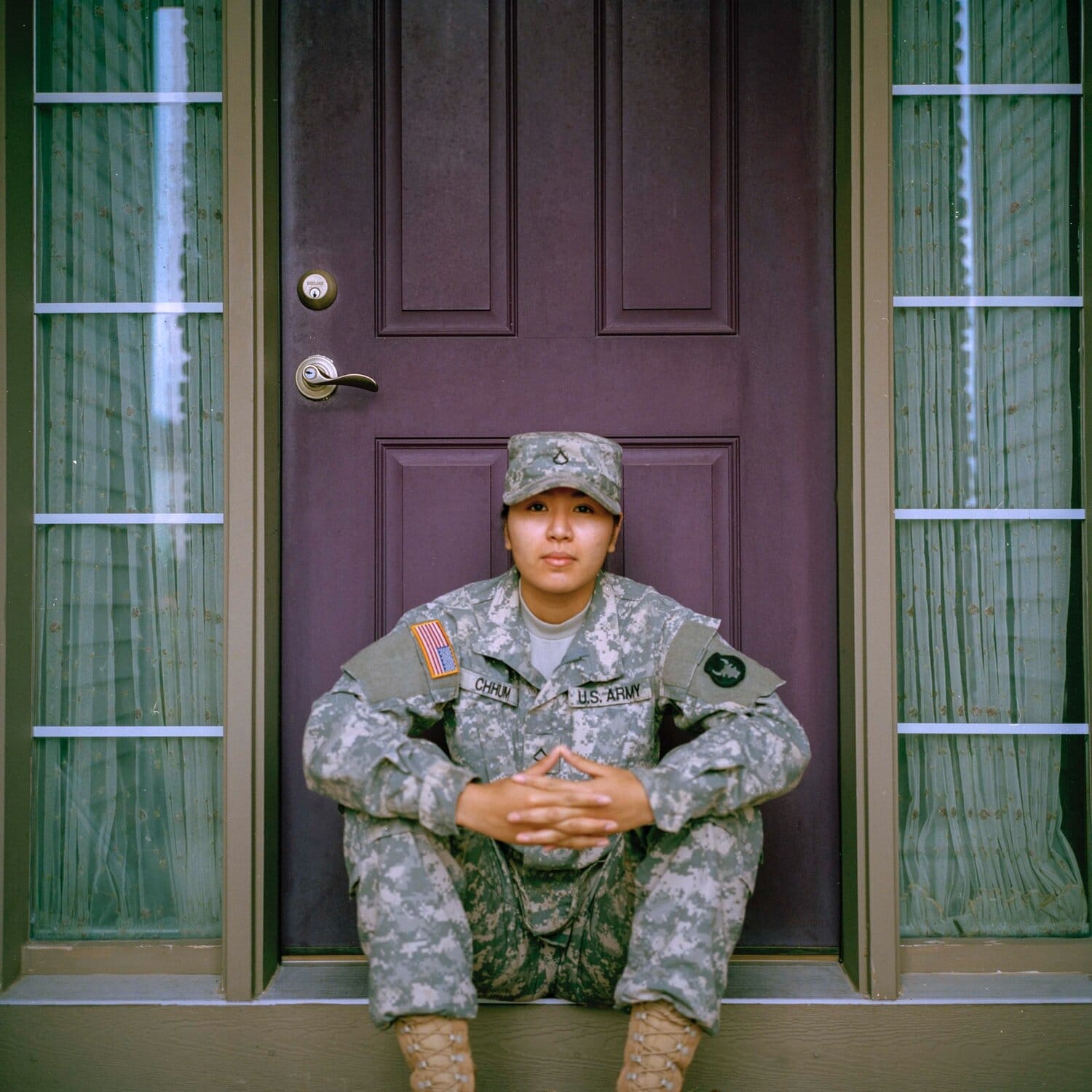 Photo of a female-presenting soldier sitting on a front porch
