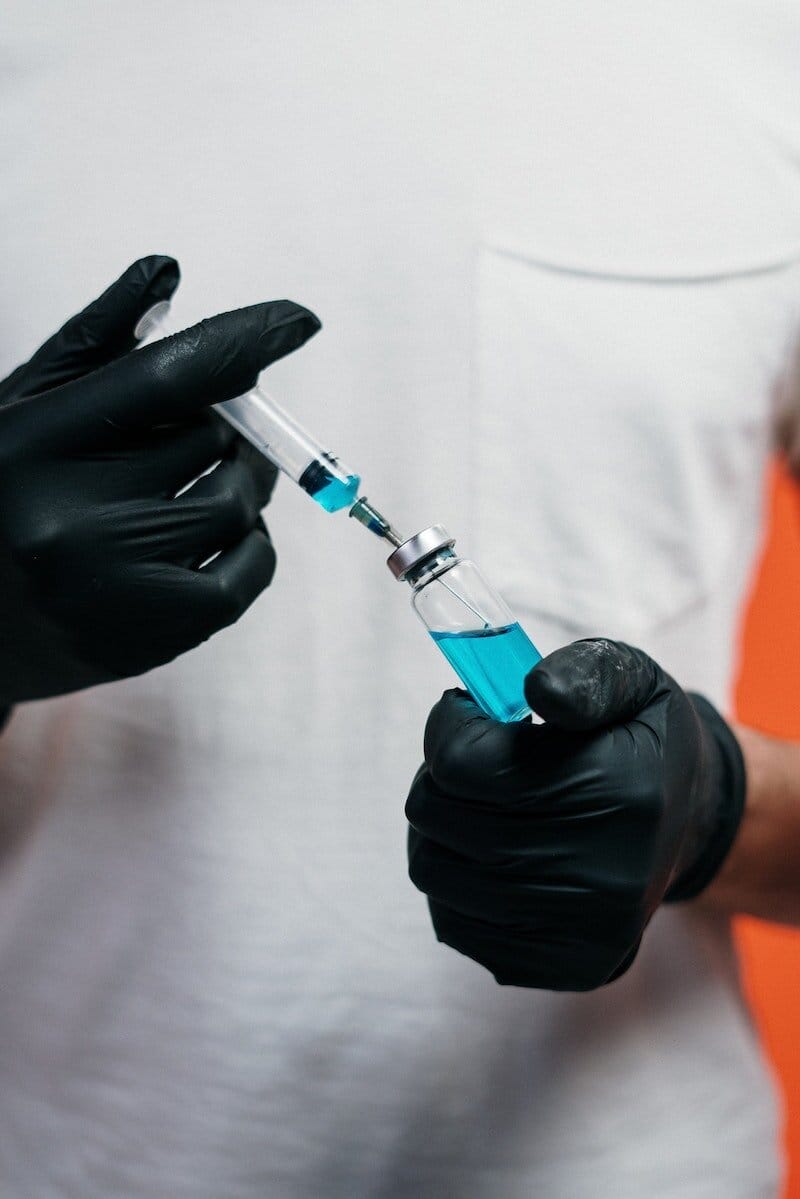 Photo of person drawing fluid into a syringe from a bottle